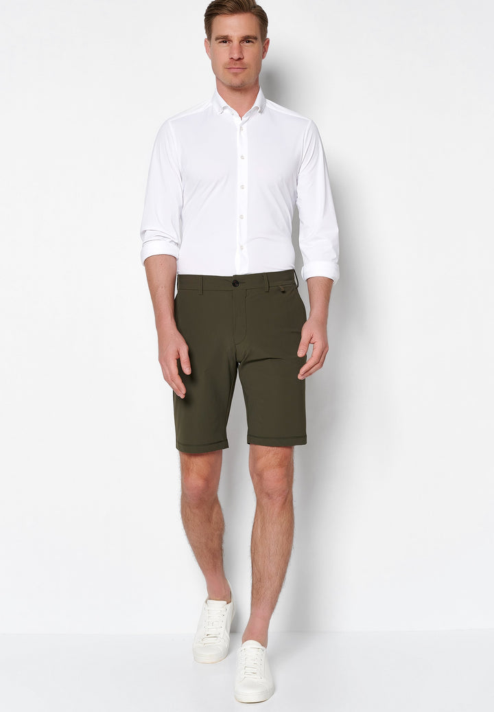 4798-92975 PURE Functional Bermuda in Grün, stilvoll kombiniert mit weißem Hemd und Sneakers. Perfekte Herren-Shorts für einen eleganten Freizeitlook.