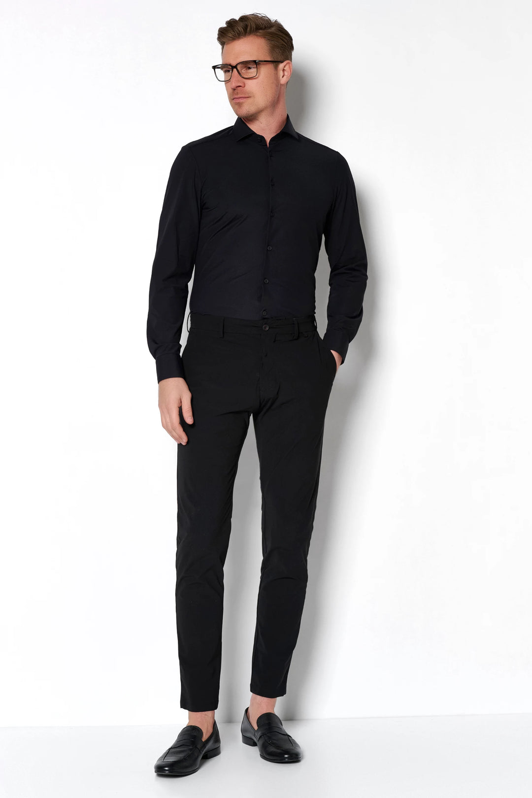 Schwarze Herren Funktionshose mit modernem Schnitt, kombiniert mit einem schwarzen Hemd. Leicht, atmungsaktiv und ideal für Reisen.